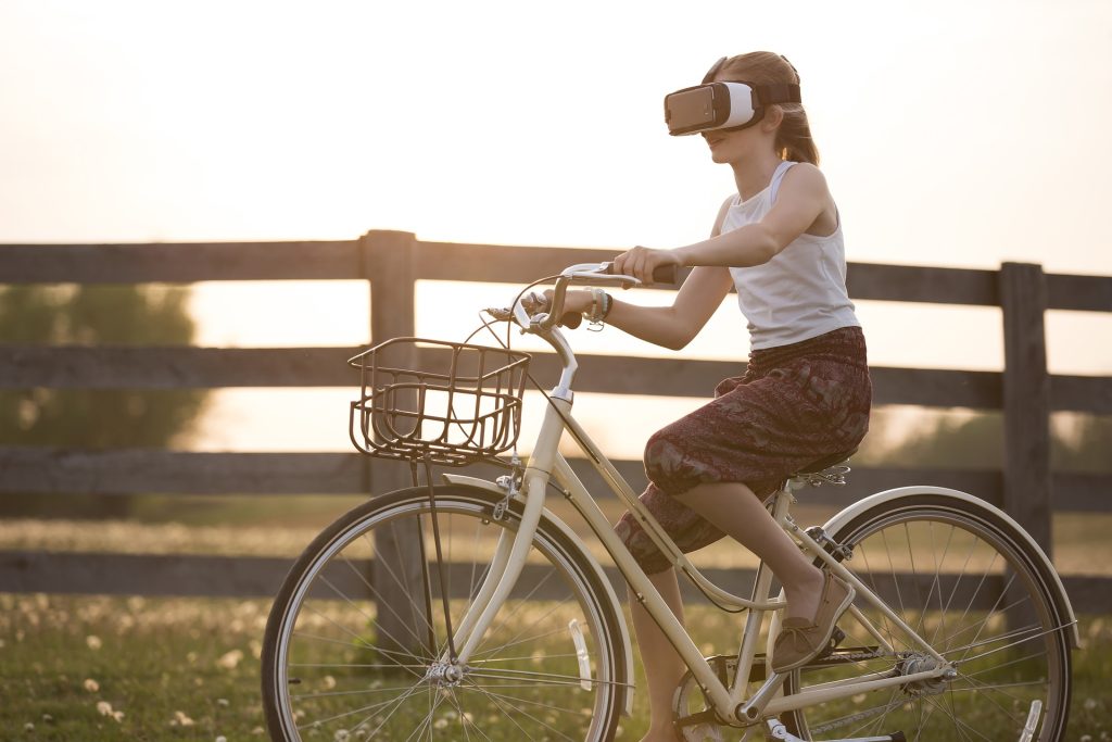 Girl is driving bicycle having virtual reality -glasses on her eyes