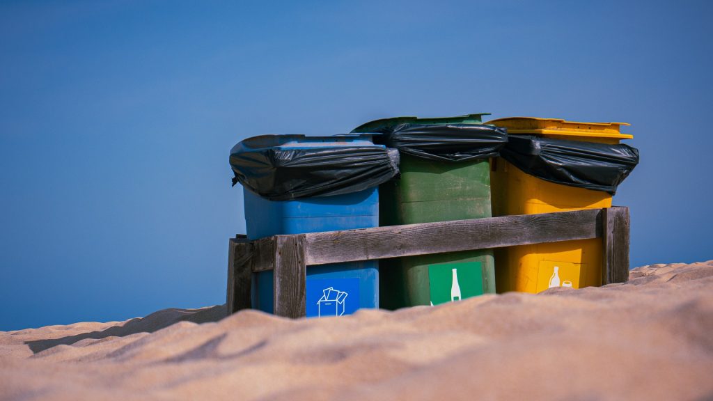 Recycling bins in the middle of the sand