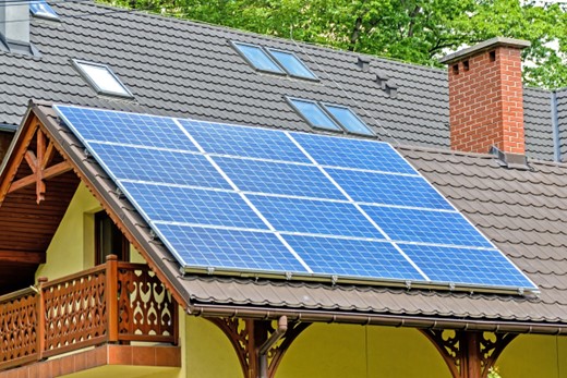 A residential house with solar panels installed on its roof. The solar panels are positioned to capture sunlight and convert it into renewable energy.